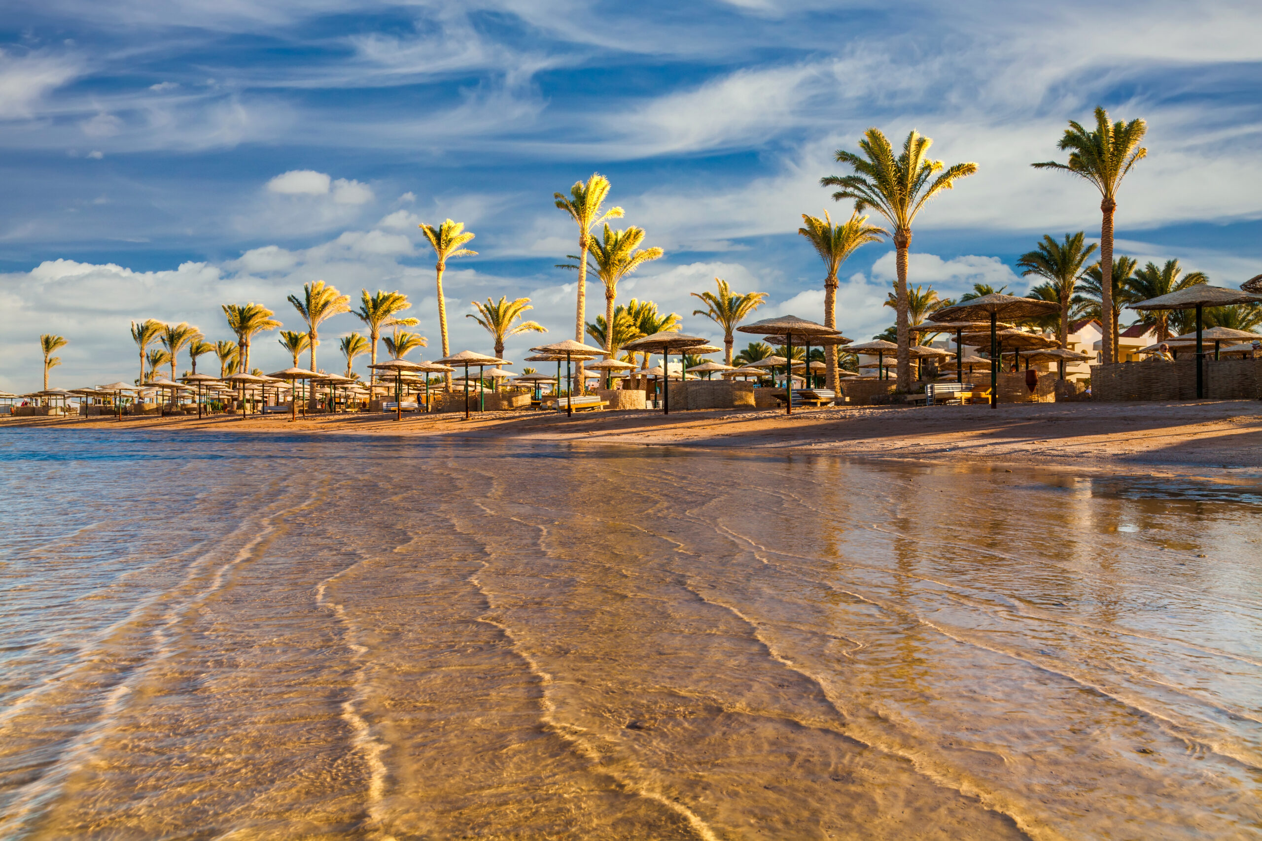 Sunset,At,The,Beach,With,Palm,Trees,,Parasols,And,Sunbeds